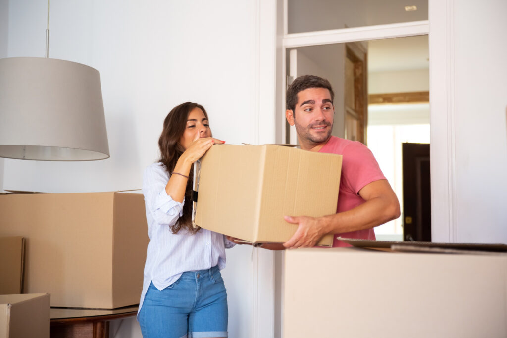 young-couple-moving-into-new-house-carrying-carton-boxes